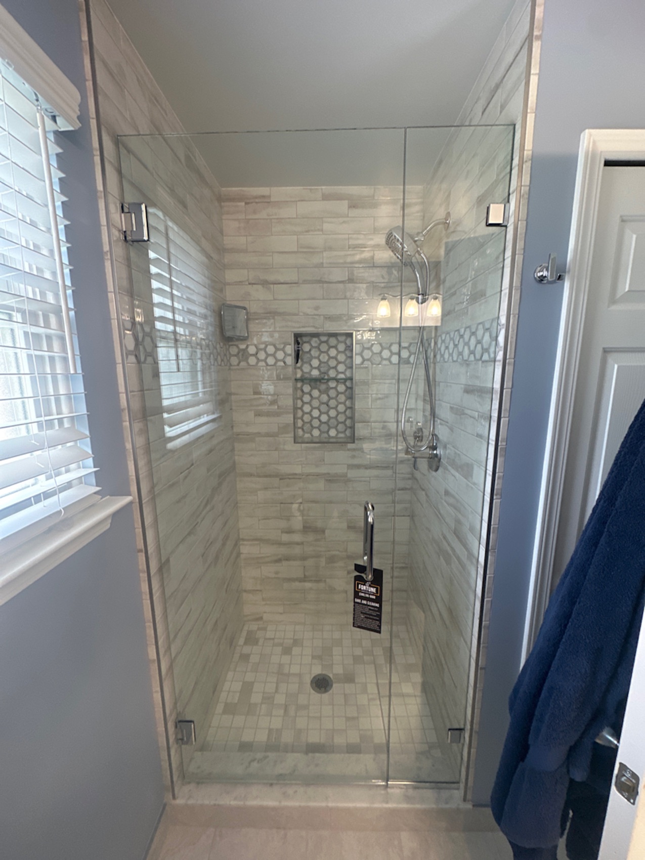 Swing glass shower door with polished chrome hardware on marble tile